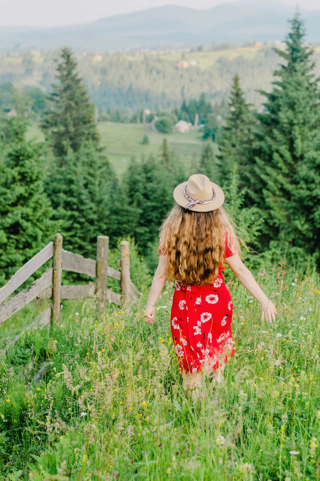 woman in red and white floral dress standing on green grass field during daytime