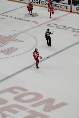 Two hockey players skate hard after the puck during an indoor game, showing the speed fans see up close at a college hockey game
