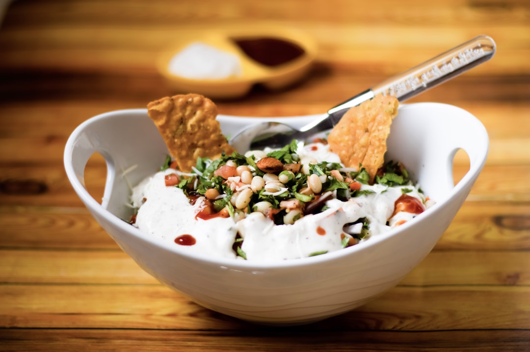 white ceramic bowl with food and stainless steel spoon