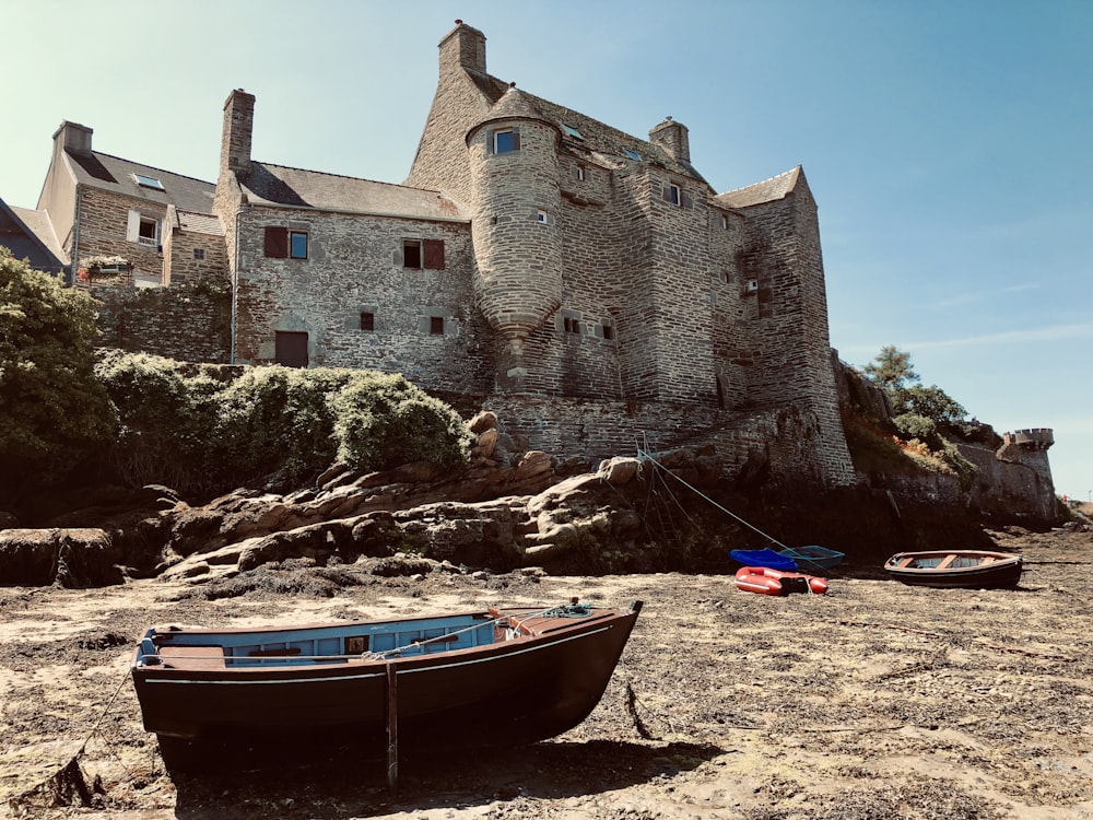 brown boat on shore near brown concrete building during daytime