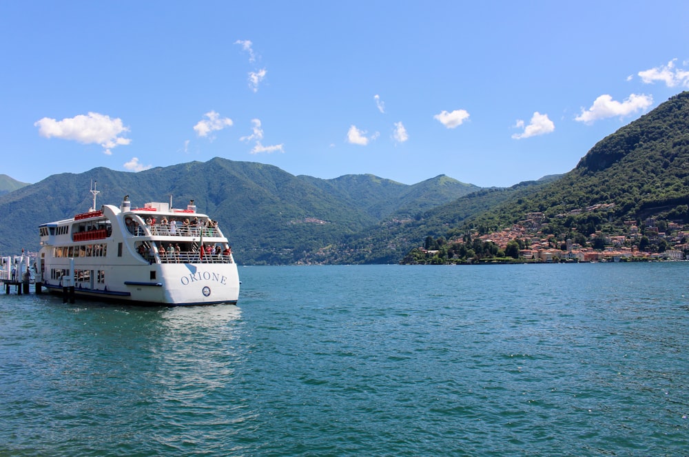 white boat on sea near green mountains under blue sky during daytime