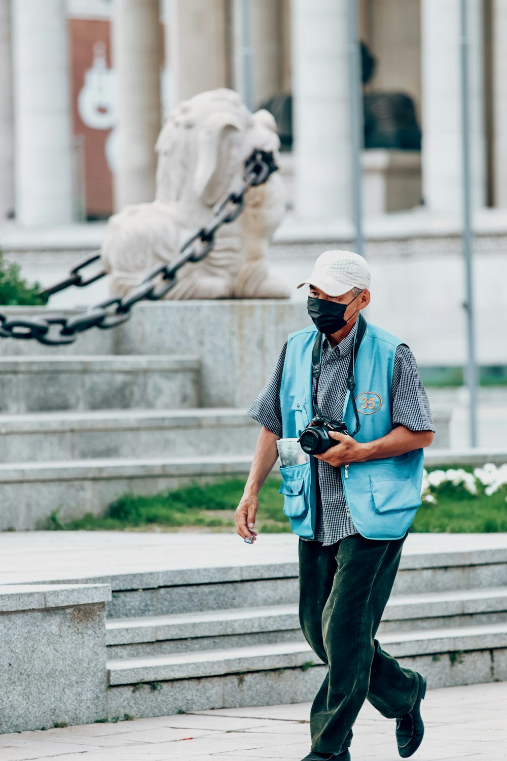 man in blue and white checkered button up shirt and black pants walking on gray concrete