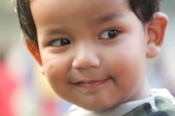 A minimalist portrait of a child with a soft, serene expression, set against a light cream background.