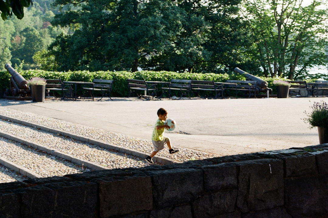 girl in yellow shirt and white shorts standing on concrete wall during daytime