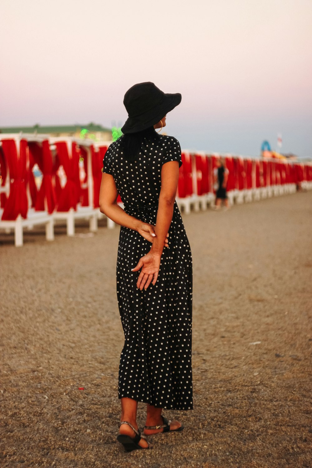 woman in black and white polka dot dress standing on brown sand during daytime