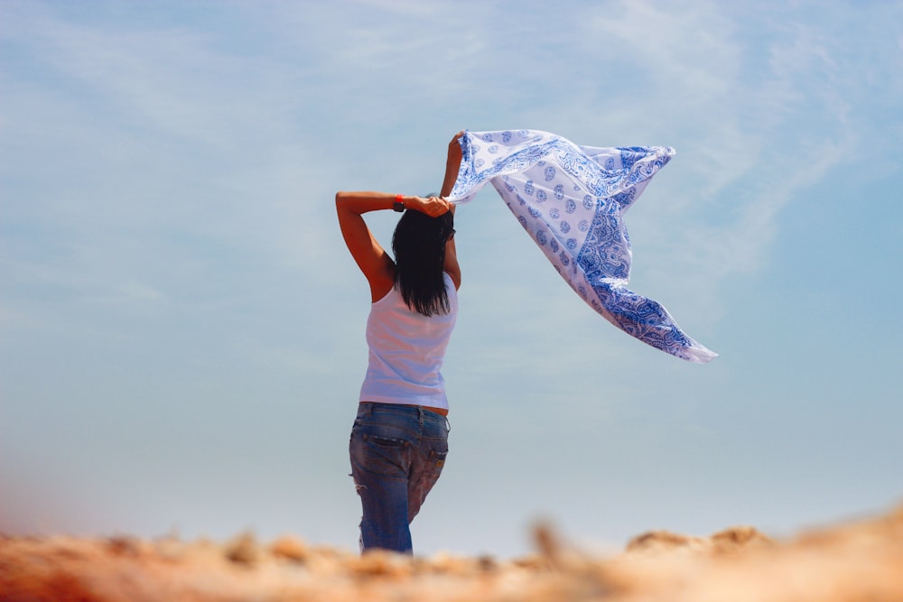 woman in white t-shirt and black pants holding blue and white scarf