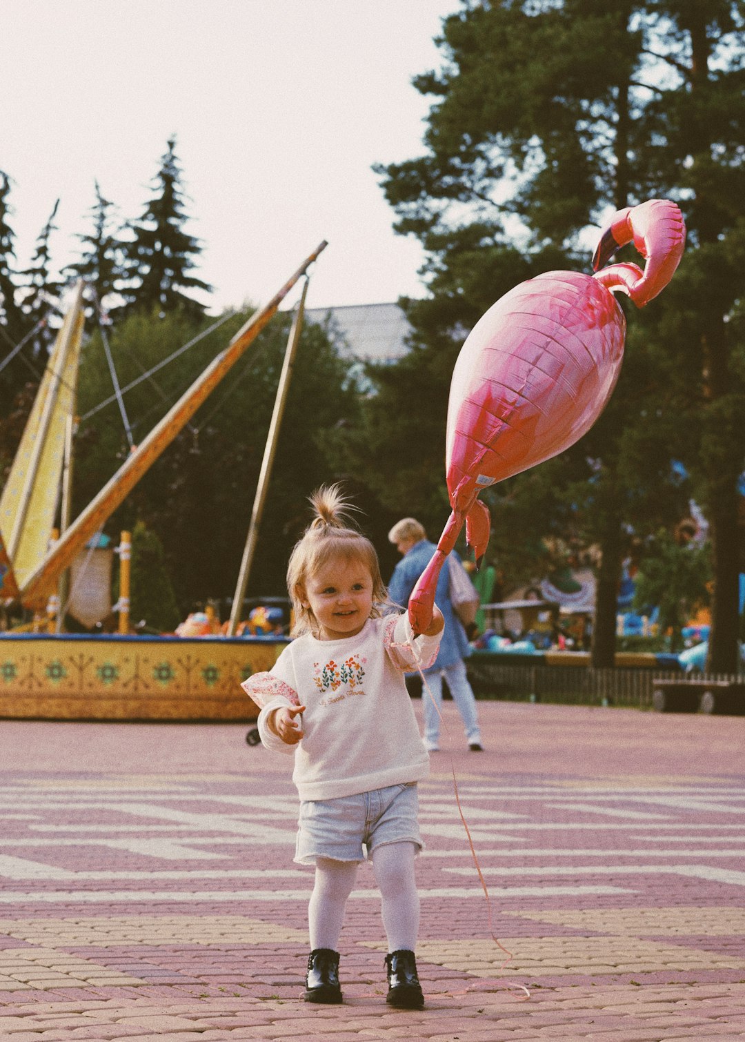 girl in white long sleeve shirt holding pink balloon