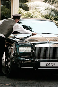 Close-up of a technician carefully polishing a shiny car hood.