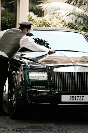 A professional technician carefully polishing a sleek car parked outside a modern apartment building.