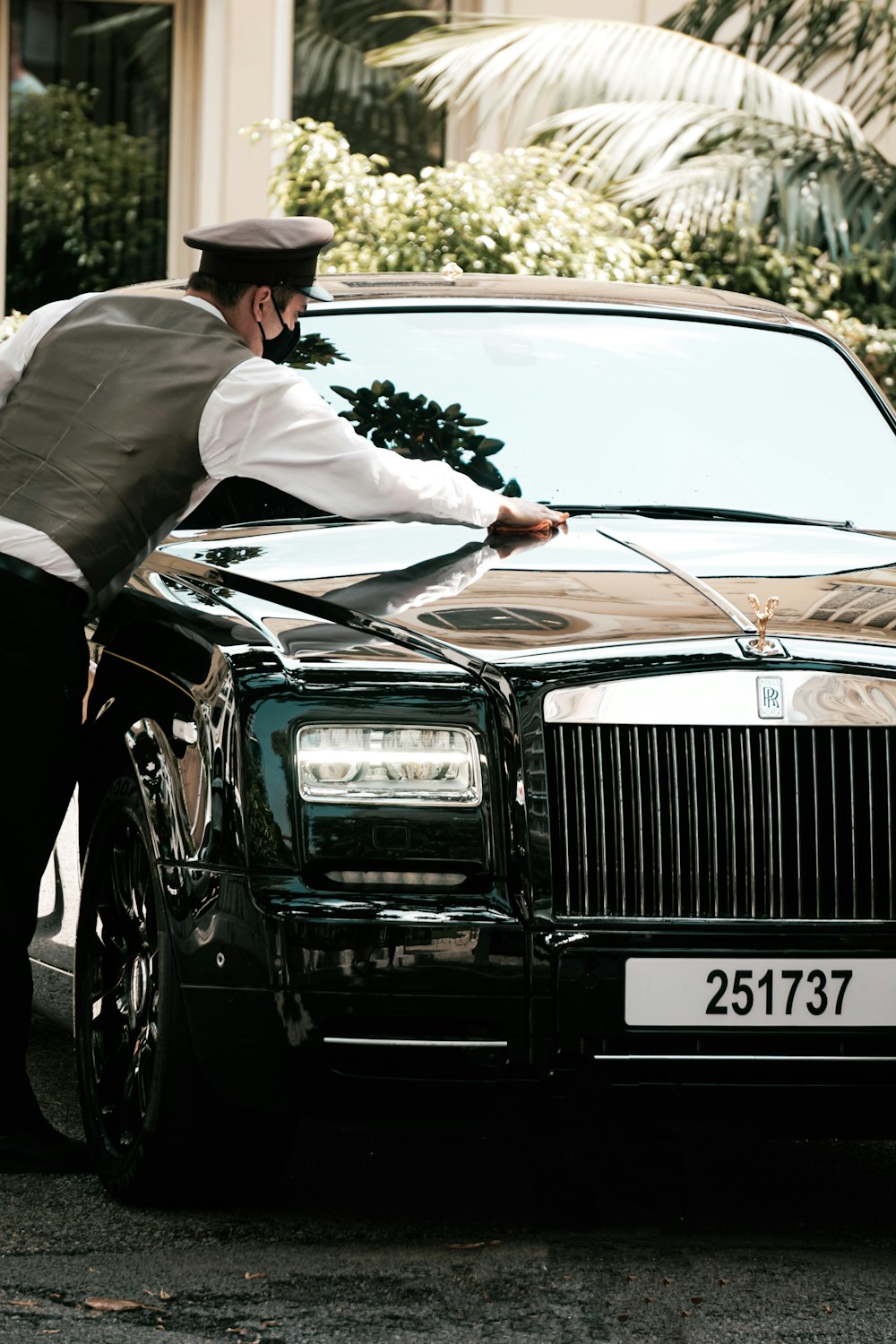 man in white long sleeve shirt and black hat standing beside black car during daytime