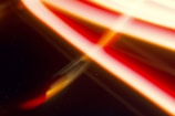 Streaks of red, yellow, and white light blend over a dark background, creating an abstract, flowing design.