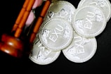 A group of silver coins inscribed with 'EXU' are scattered on a dark surface. An hourglass with wooden supports is partially visible, positioned diagonally on the left side.