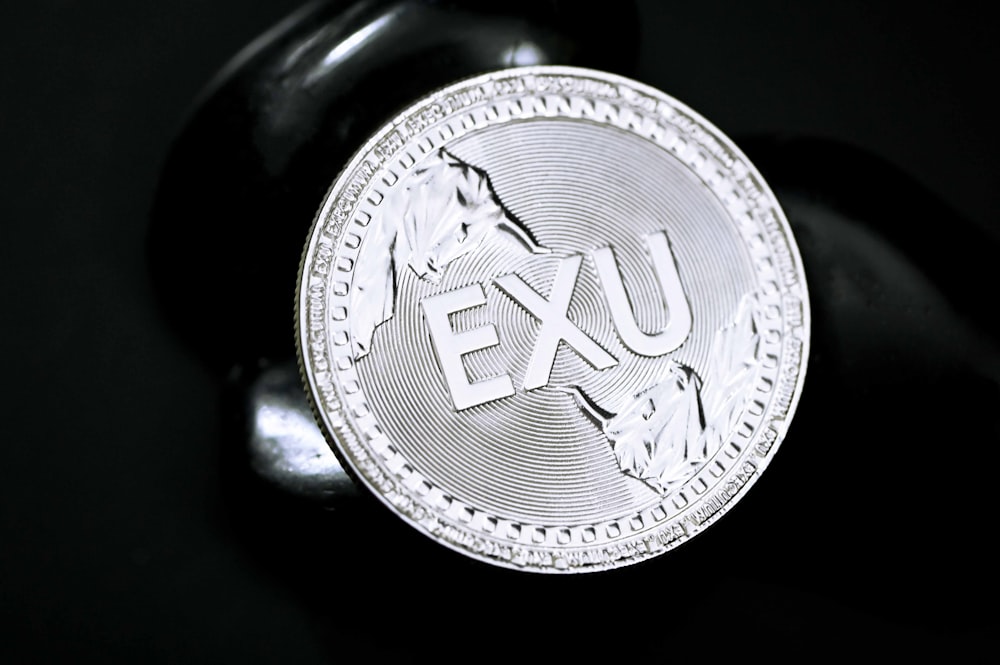 silver round coin on black surface