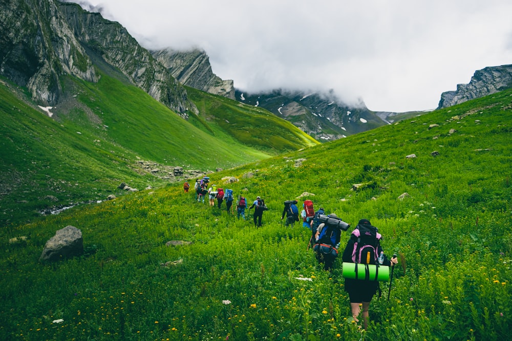 people hiking on green grass field during daytime