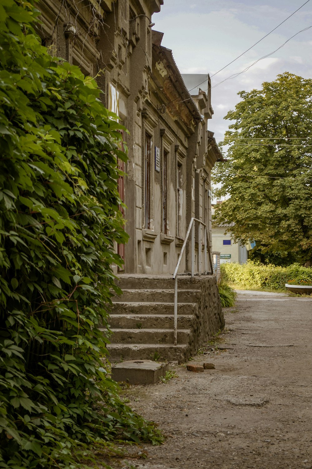 gray concrete stairs between green trees and brown concrete building during daytime