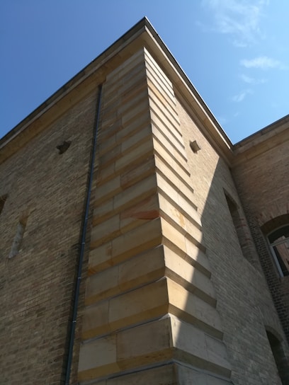 A mason carefully laying bricks on a sunny residential project, showcasing detailed craftsmanship.