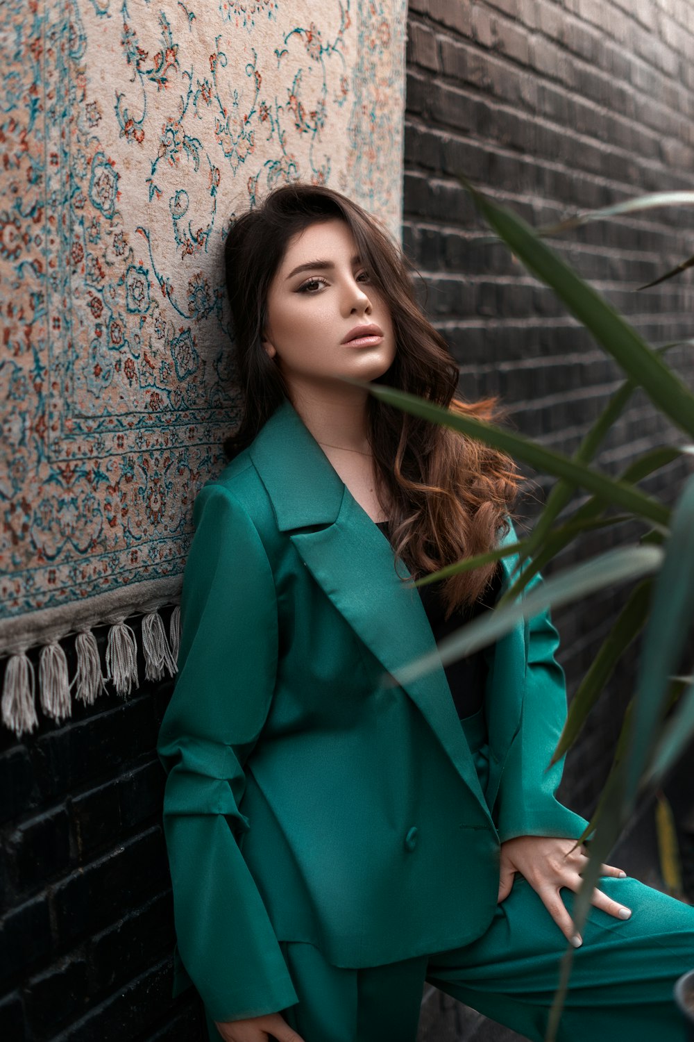 woman in green blazer standing beside green plant