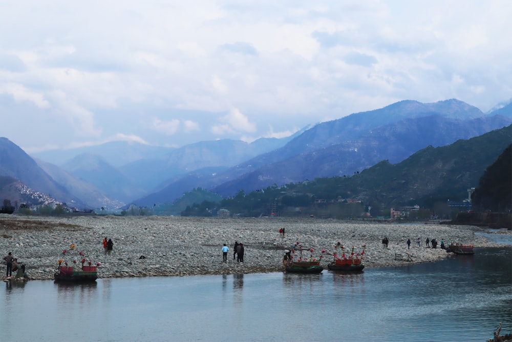 people on body of water near mountains during daytime
