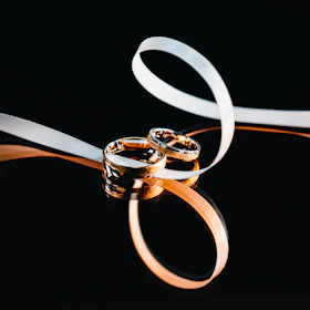 Elegant custom wedding bands intertwined on a rustic wooden surface, highlighting fine metalwork.