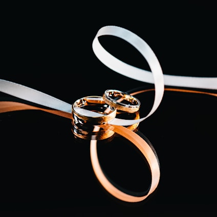 A soft pink and gold elegant logo of Slavic Marriage with intertwined rings symbolizing unity.