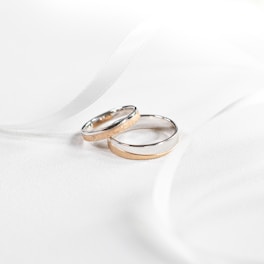 Elegant wedding bands with intricate detailing displayed on a polished wooden surface.