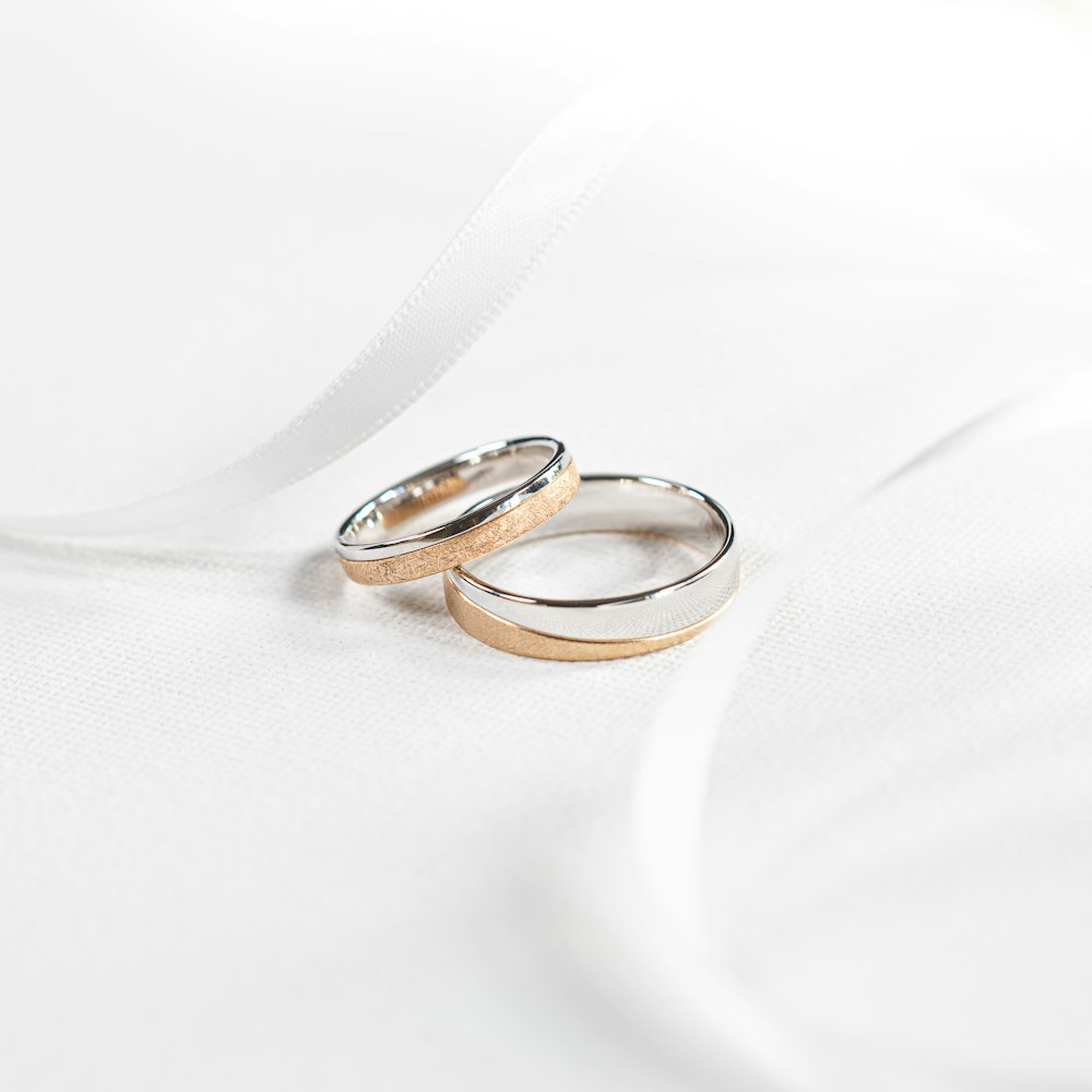 two wedding rings sitting on top of a white cloth