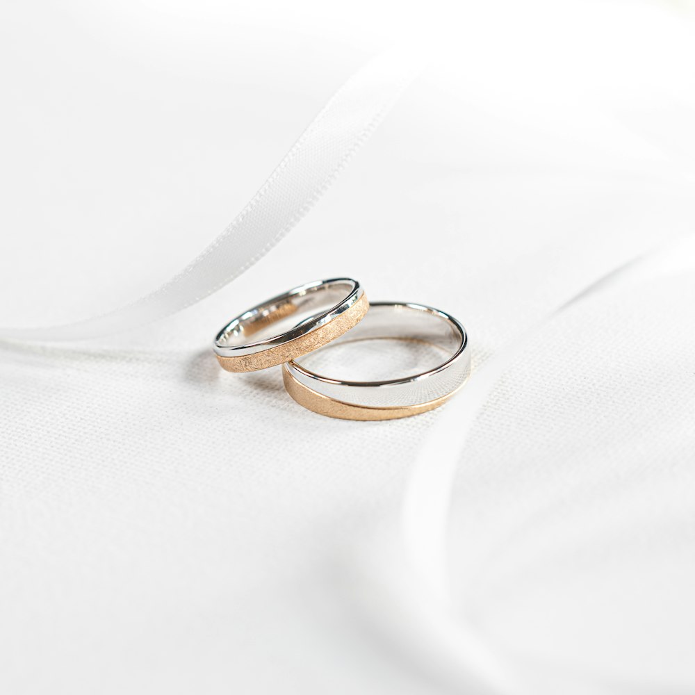Dos anillos de boda sentados encima de una tela blanca