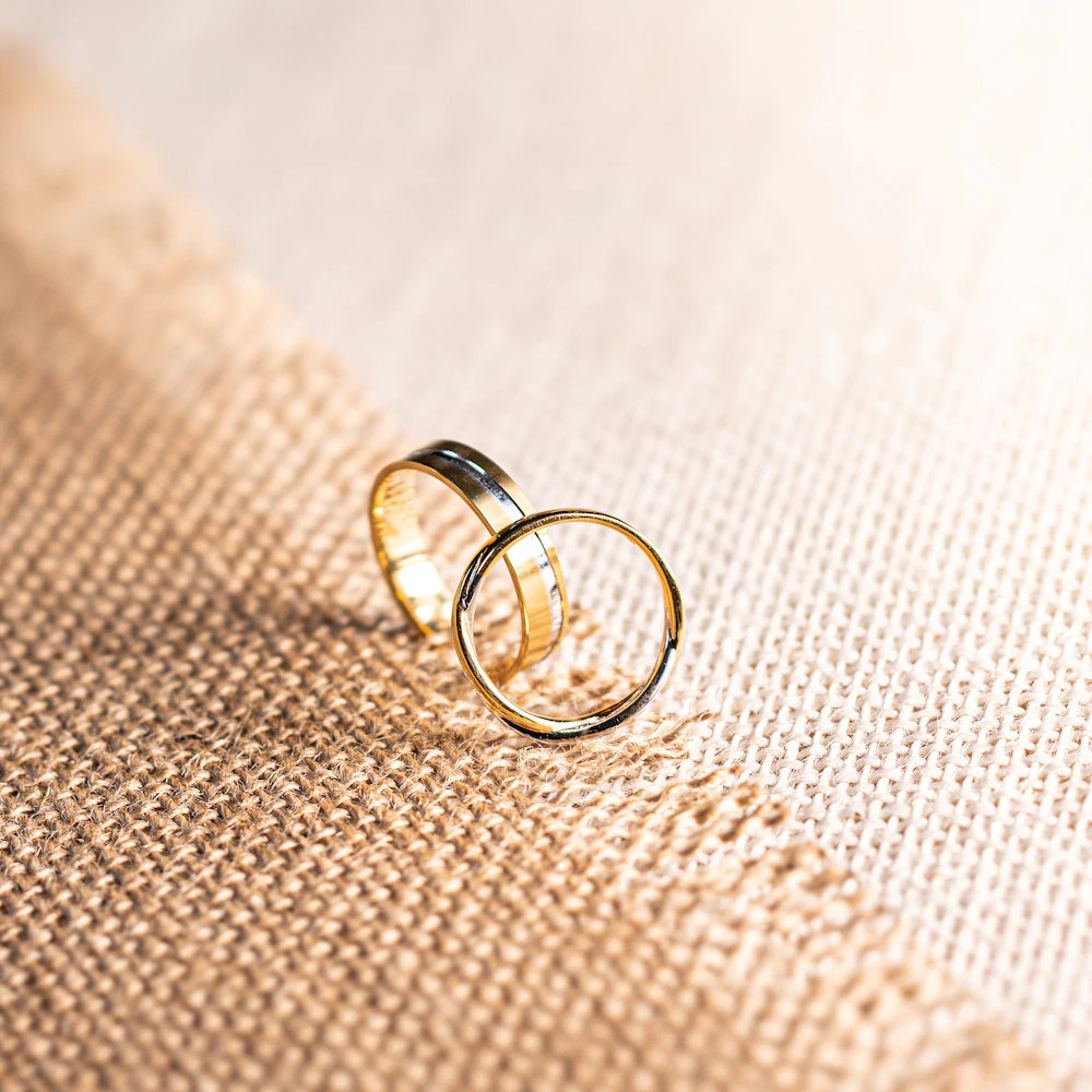 Two gold wedding rings resting on warm woven fabric