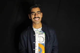 A smiling dark-skinned waiter confidently greeting happy tourists in a cozy restaurant.