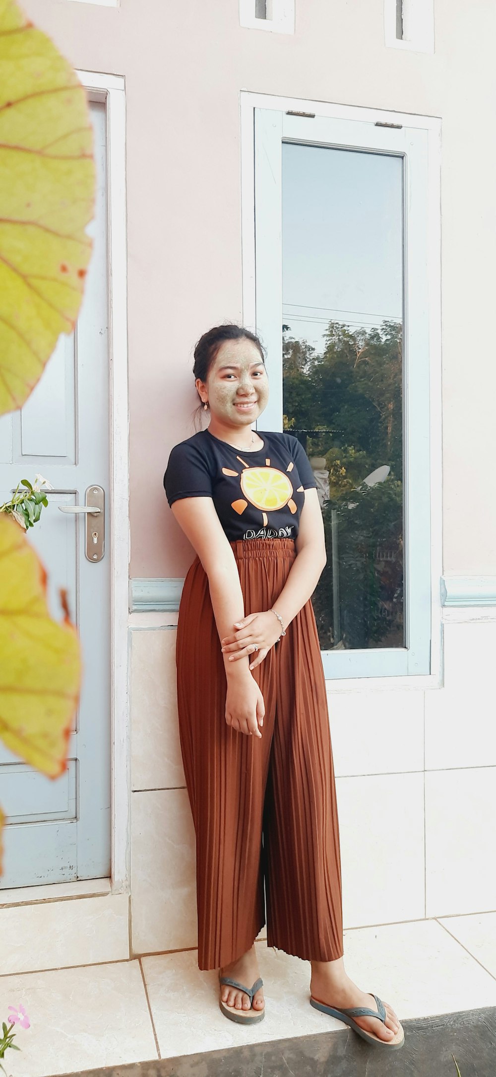 woman in black crew neck t-shirt and orange skirt standing beside white wooden framed glass