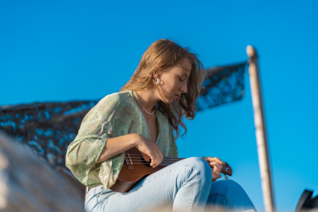 woman in gray shirt and blue denim jeans sitting on white concrete wall during daytime