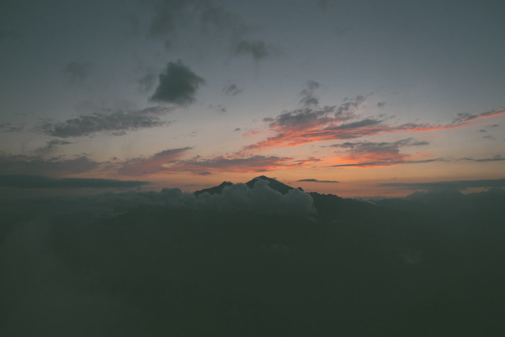 silhouette of mountains under cloudy sky during sunset