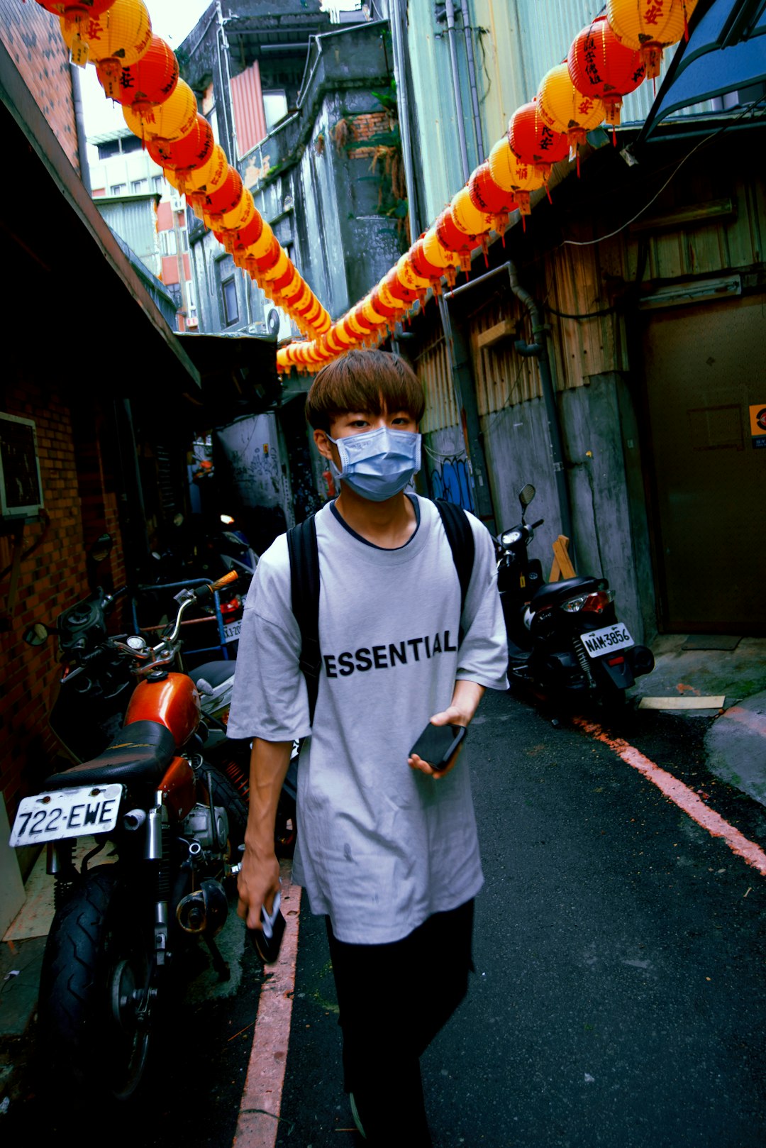 man in white crew neck t-shirt standing beside motorcycle during daytime