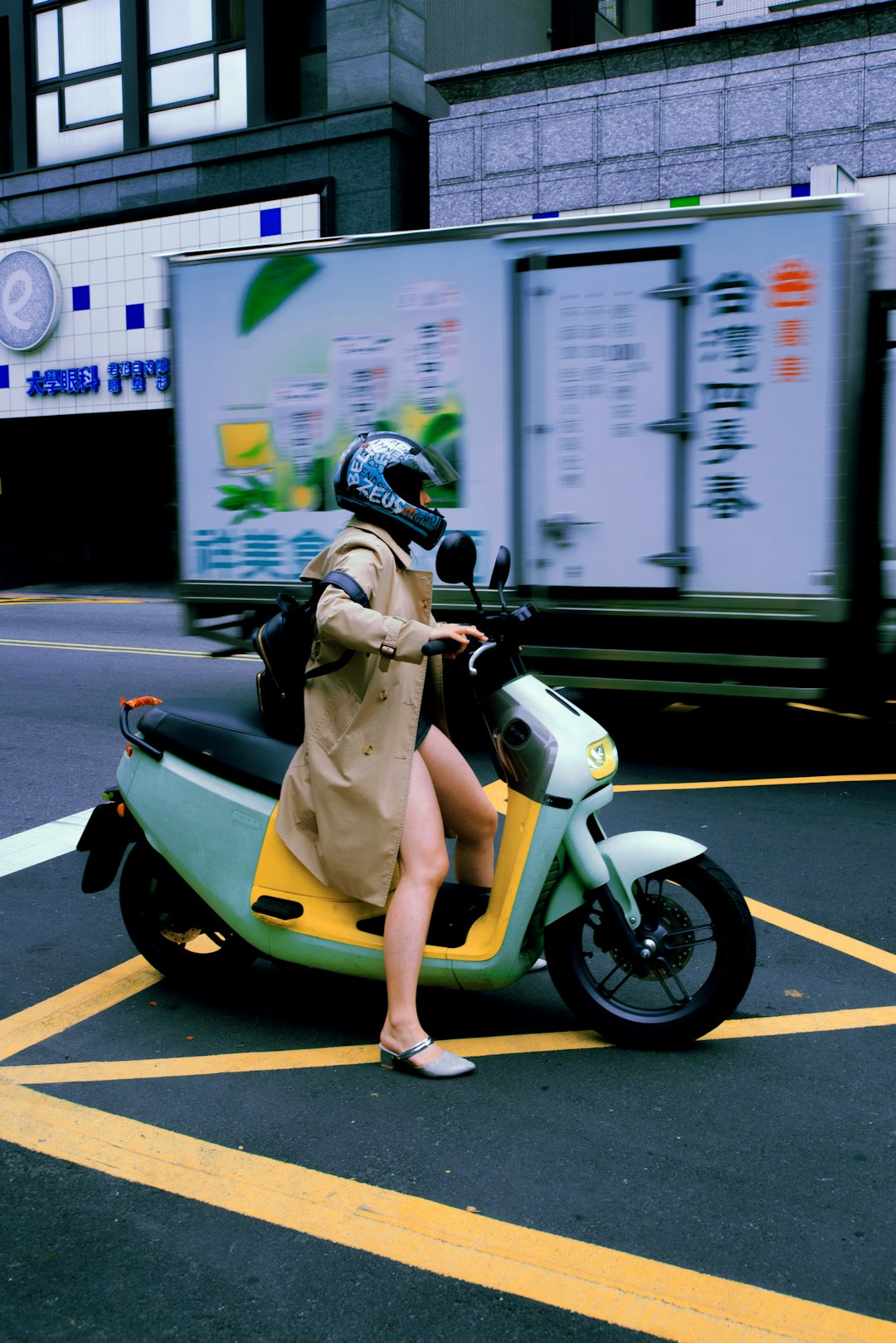 woman in yellow jacket riding yellow motor scooter during daytime