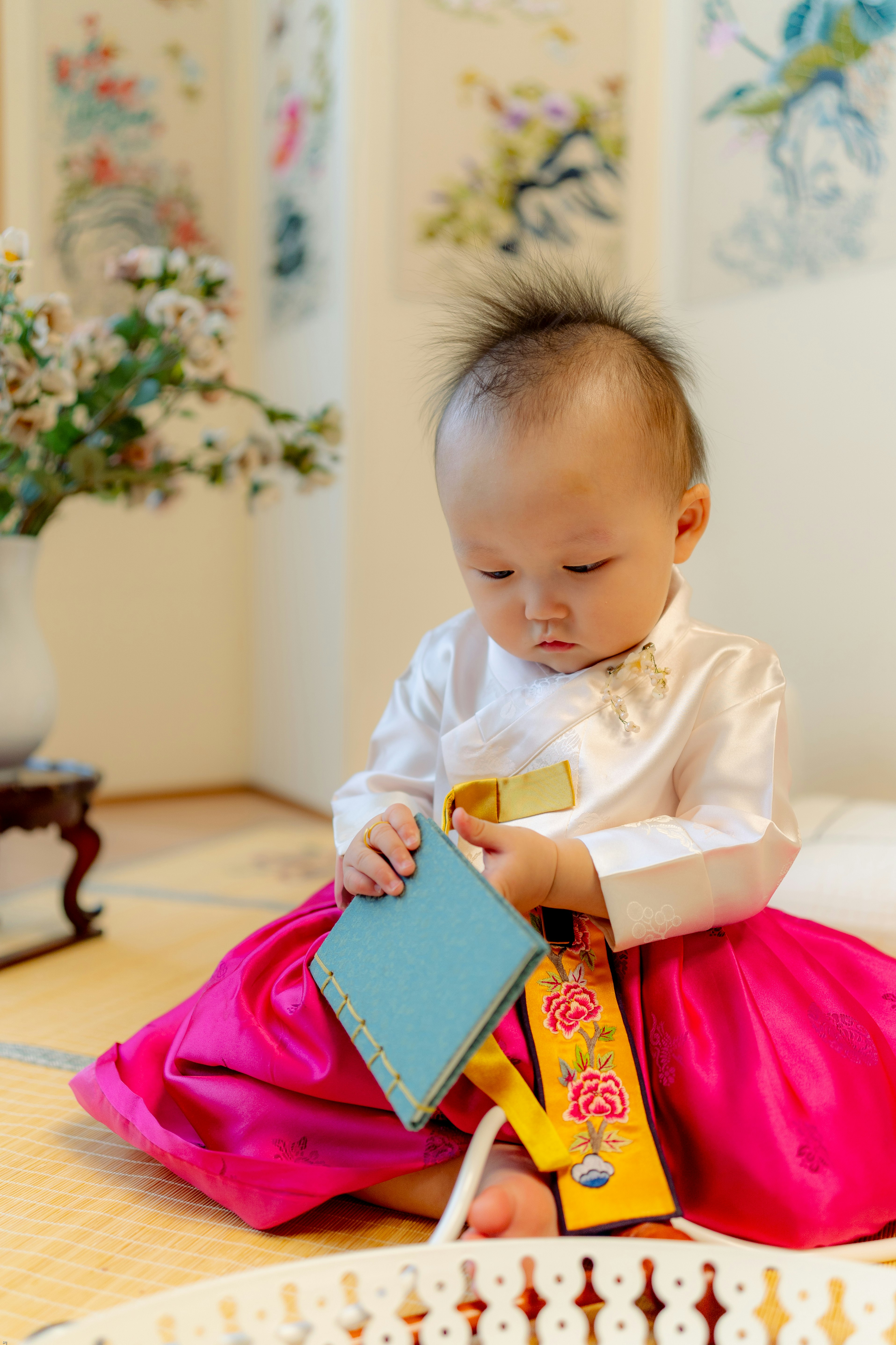 child in white dress shirt holding blue book