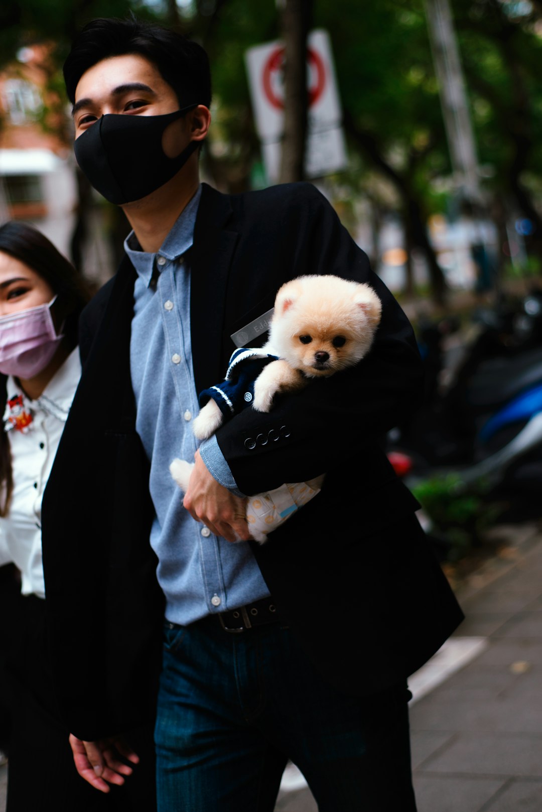 man in black suit jacket holding brown puppy