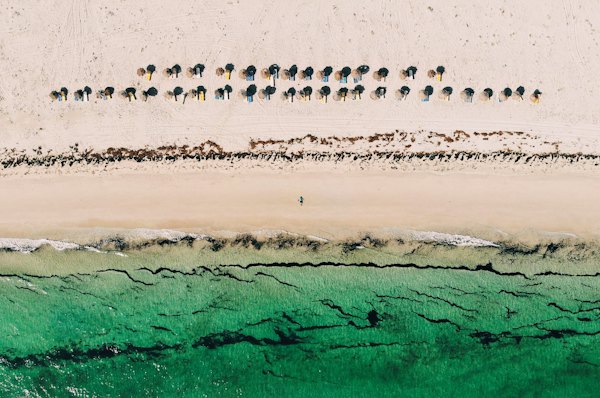 Rows of parasols along a turquoise shore, from the air — Djerba, Tunisia