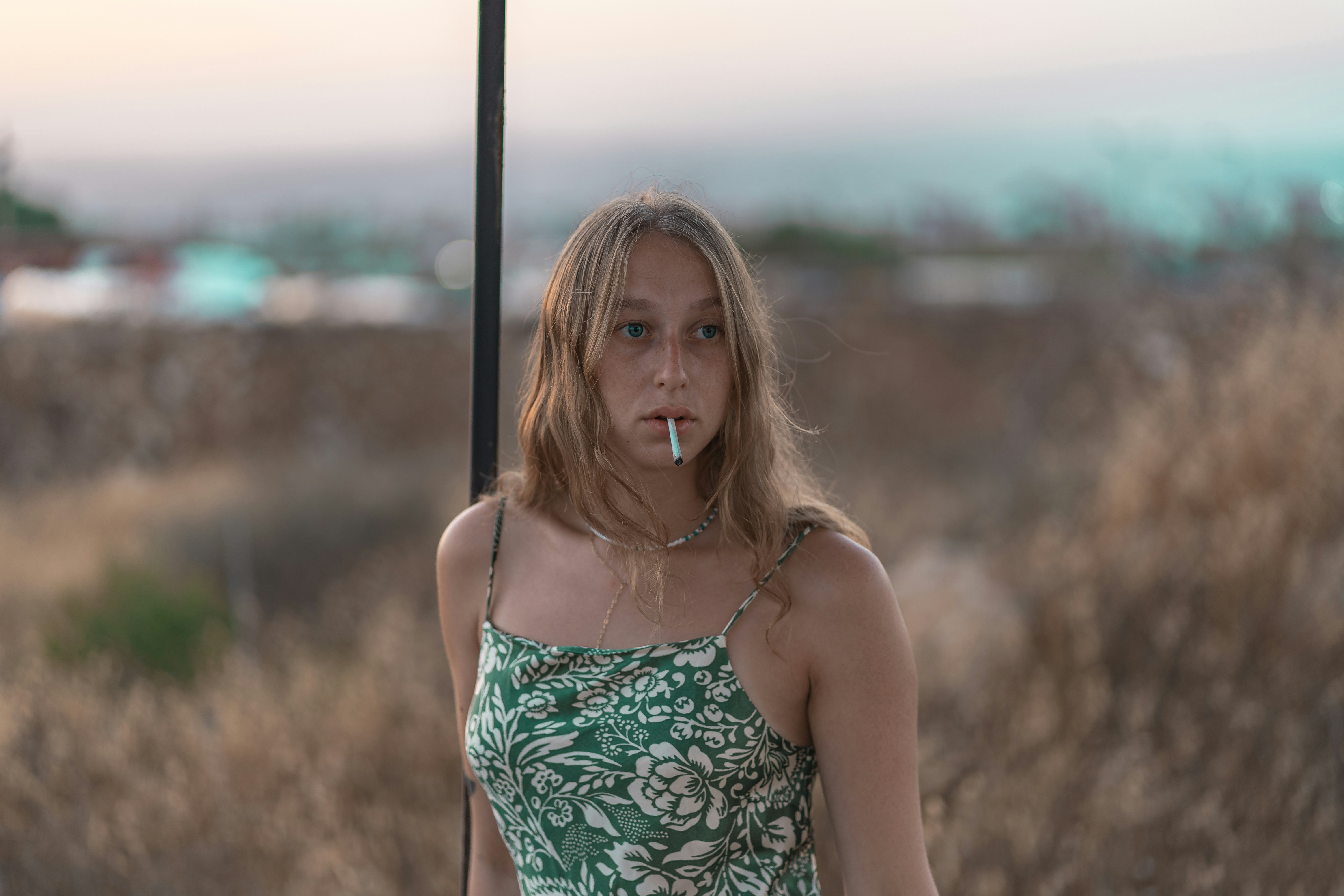 woman in green spaghetti strap top standing near black metal post during daytime