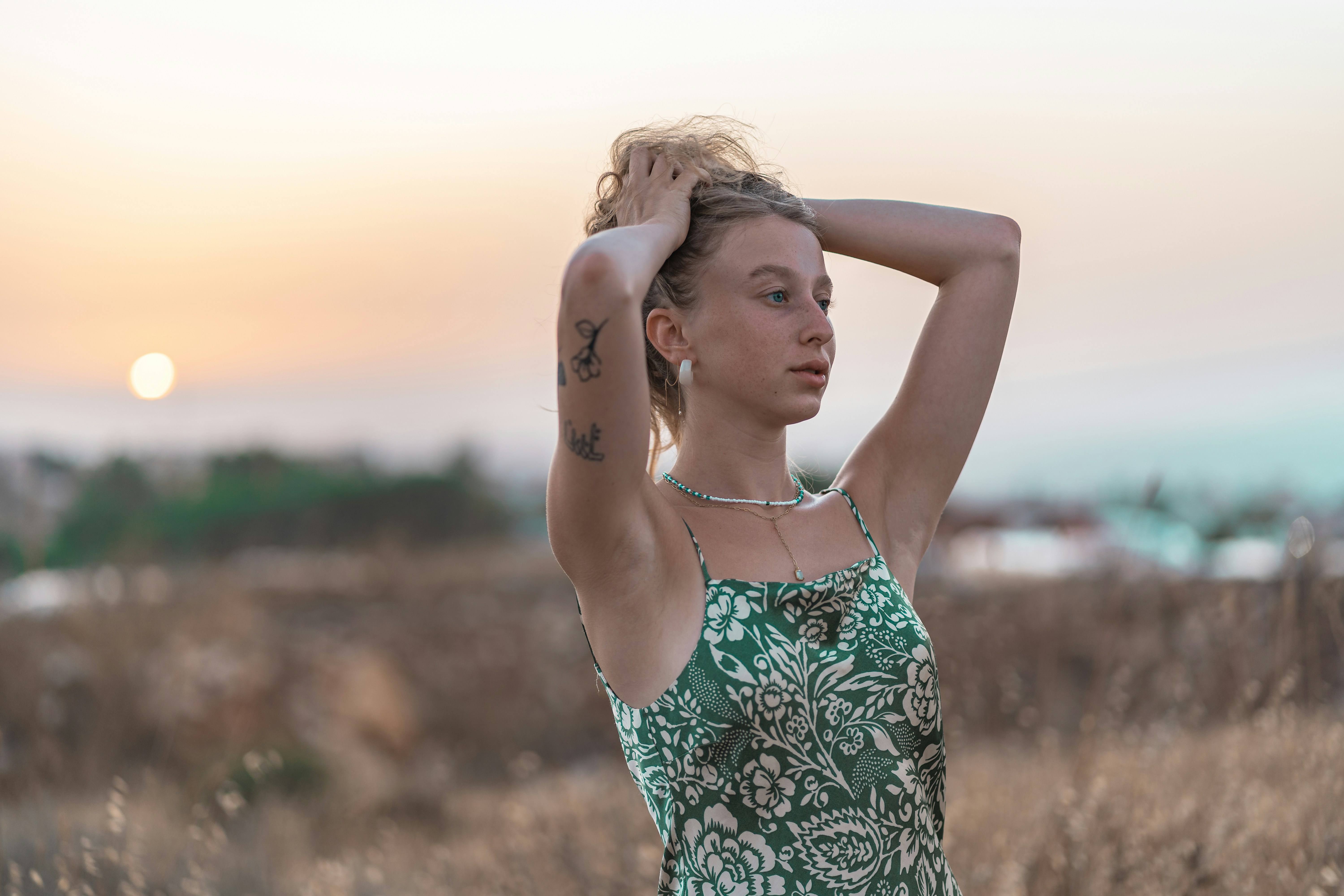 woman in green and white floral spaghetti strap top raising her right hand