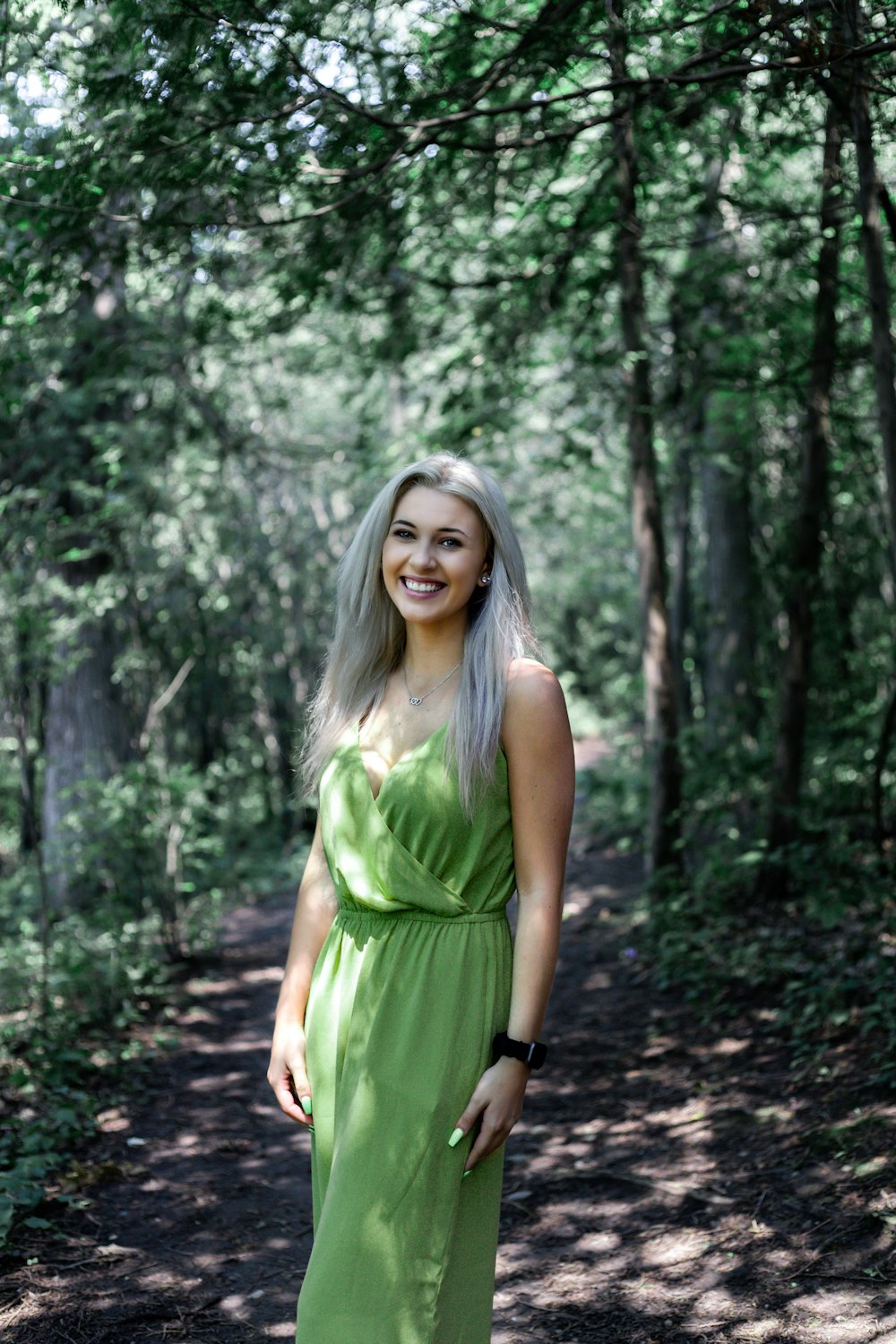 Frau in grünem ärmellosem Kleid, die tagsüber im Wald steht
