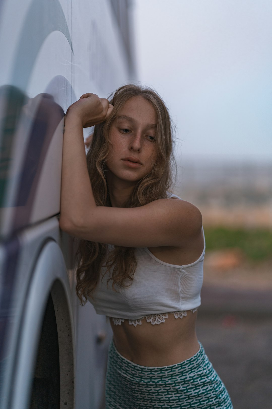 woman in white crop top and white panty leaning on white car