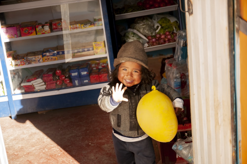 Femme en veste grise et blanche tenant un ballon jaune