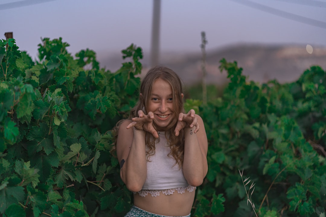 woman in white crop top and blue denim daisy dukes standing near green plants during daytime