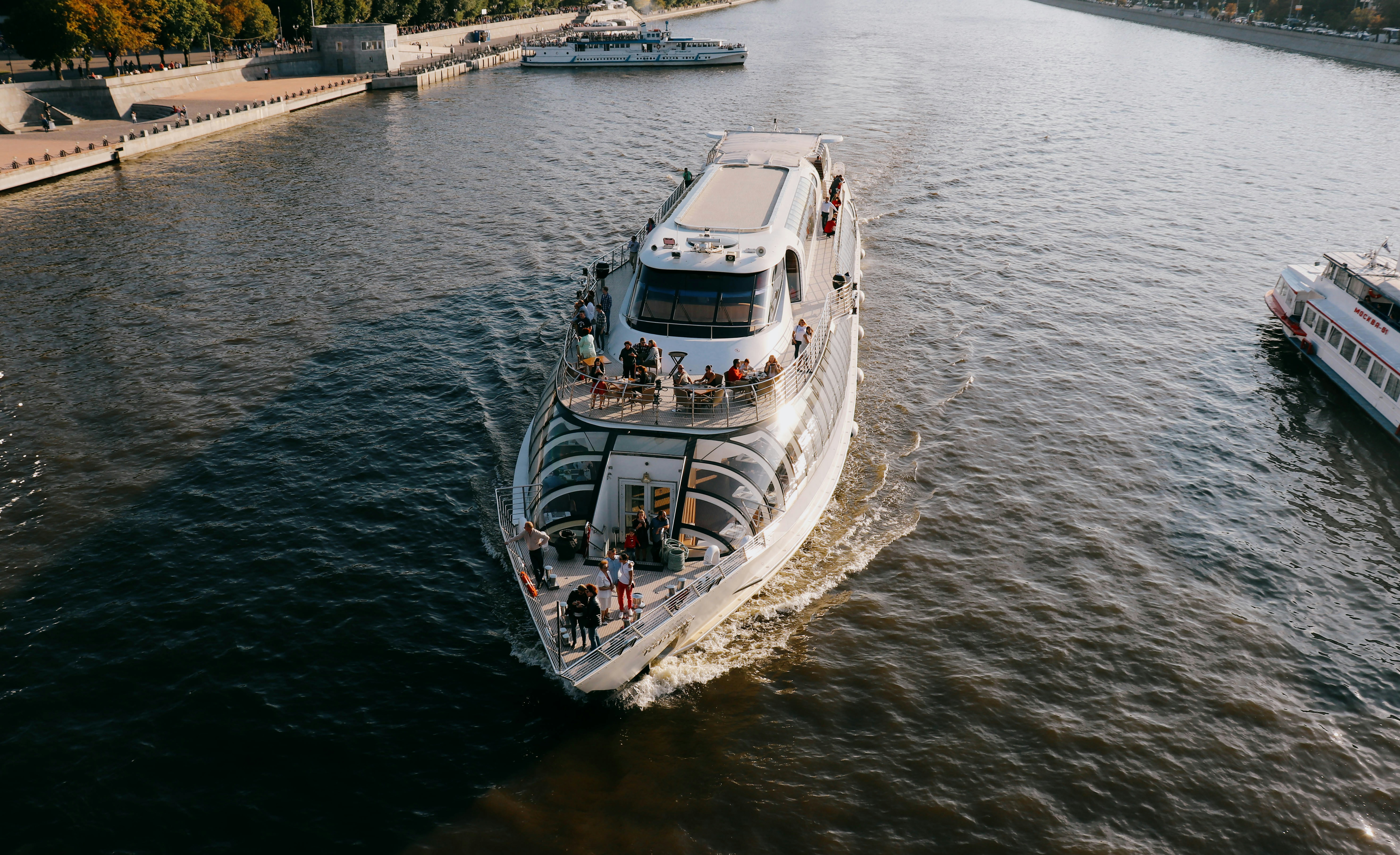 a white boat traveling down a river next to a bridge, 