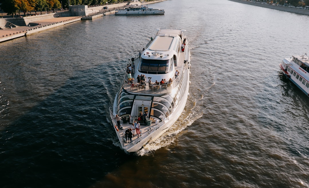 a white boat traveling down a river next to a bridge,