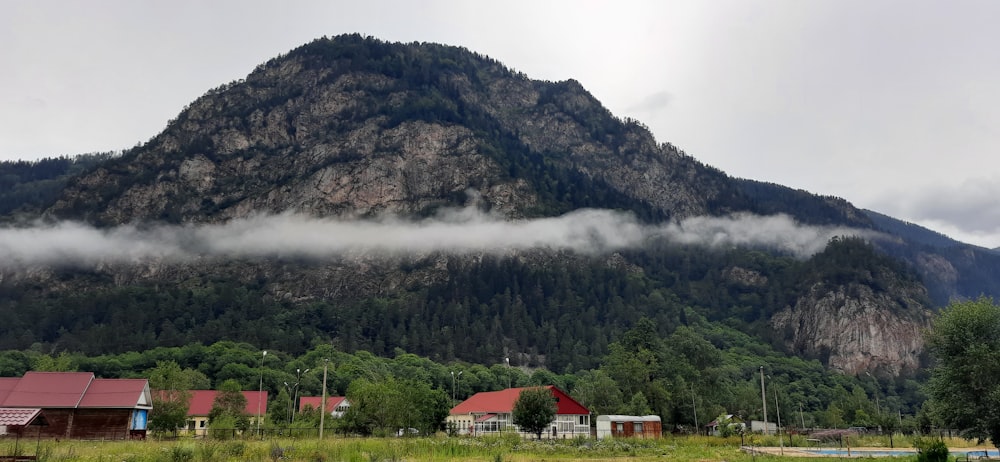 white and red house near green mountain under white clouds during daytime