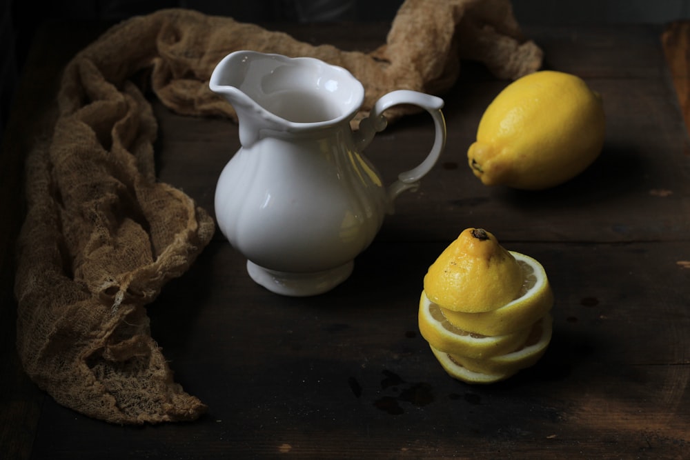 white ceramic pitcher beside yellow lemon fruit