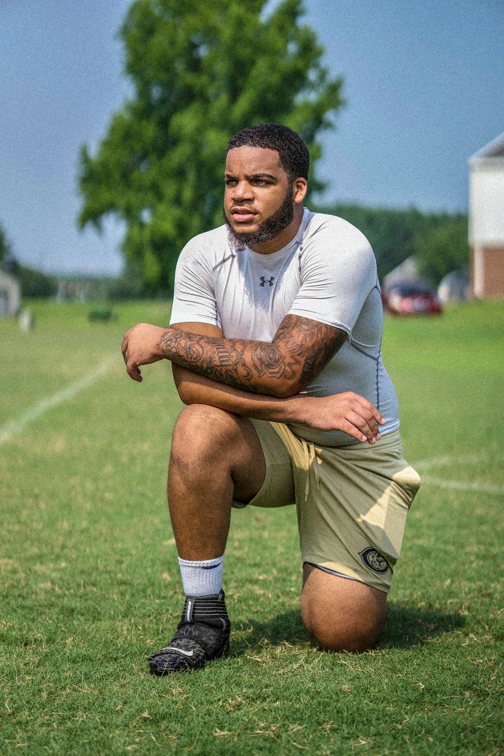 man in white polo shirt and brown shorts sitting on green grass field during daytime