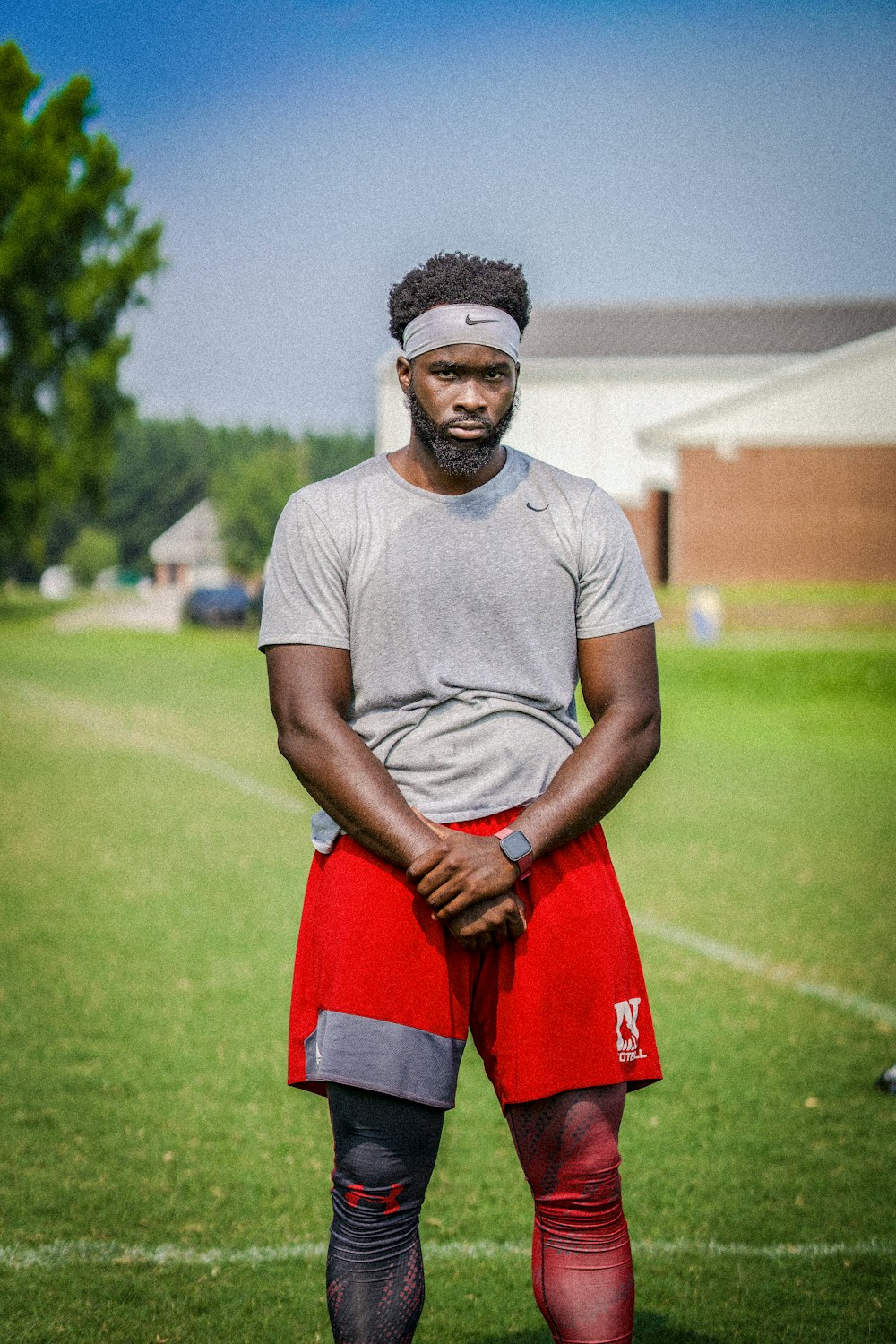 man in gray crew neck t-shirt and red shorts standing on green grass field during