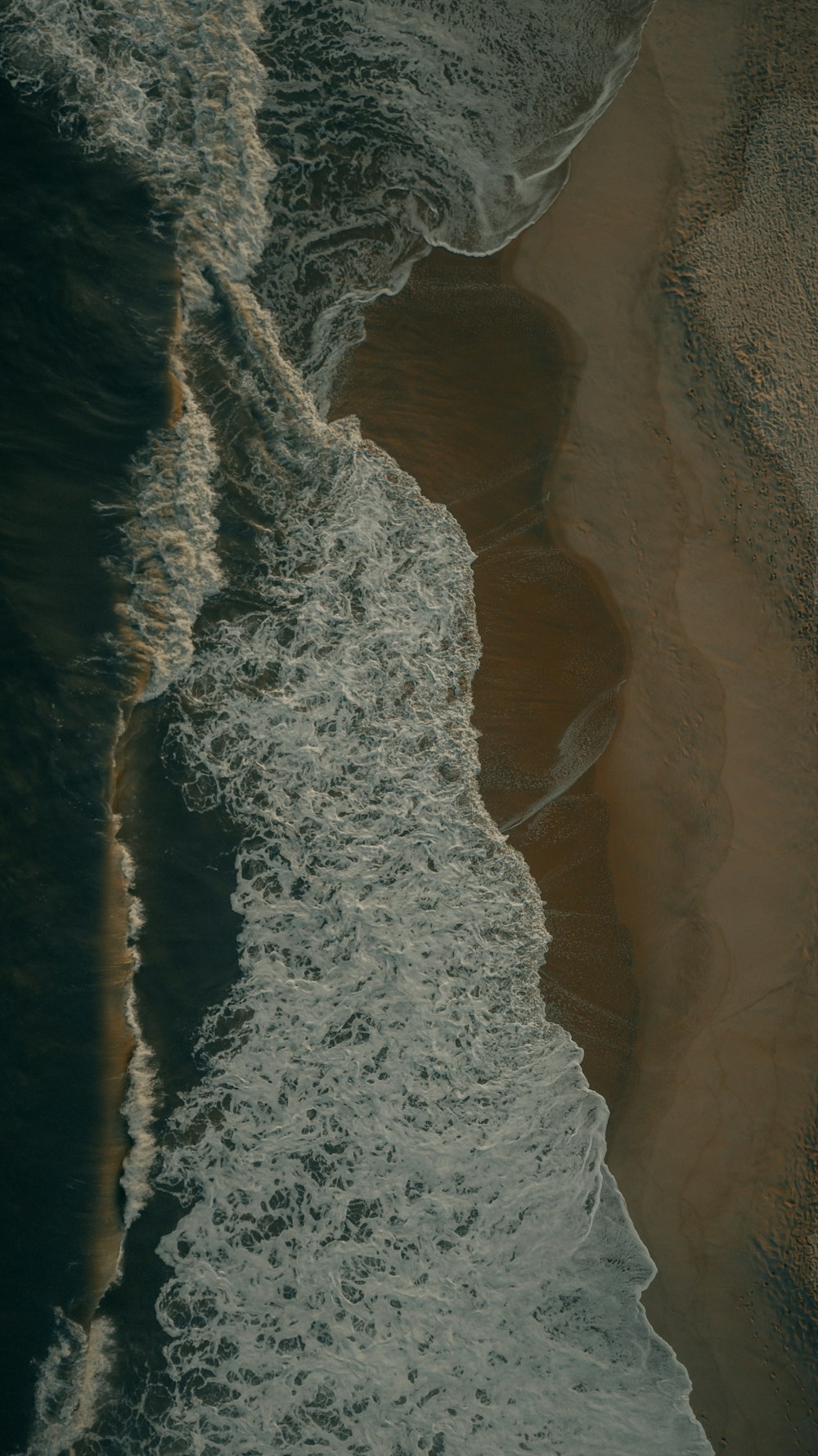 昼間に海岸に打ち寄せる海の波の空中写真